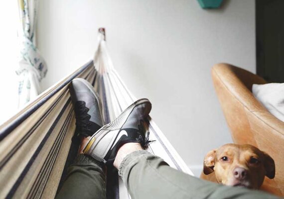 An athlete relaxing in a hammock with their dog
